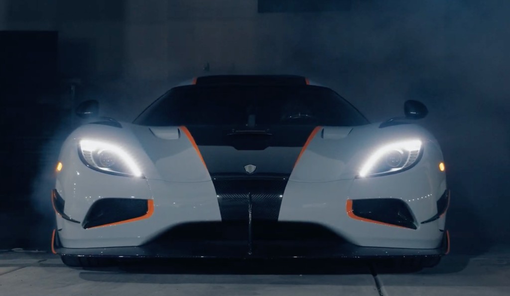 White Koenigsegg headlights glowing through smoke in a garage