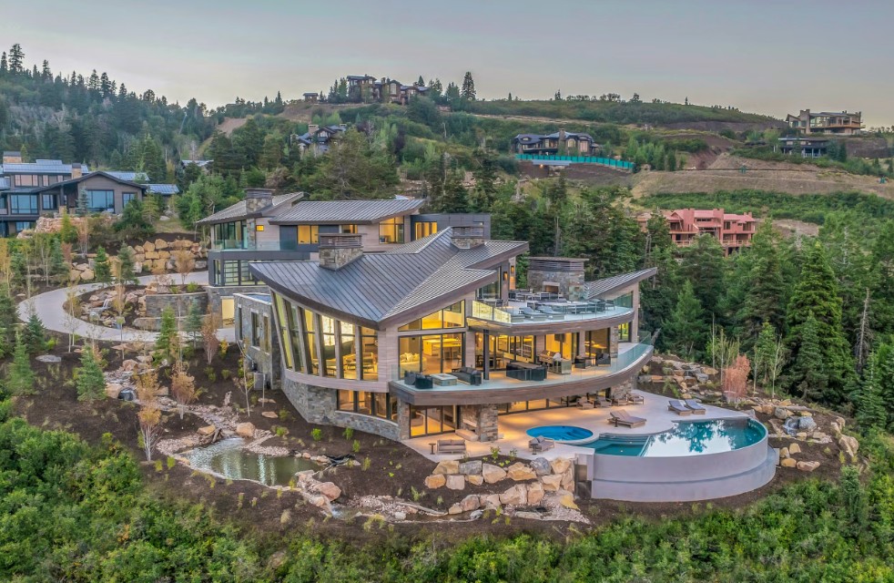 Modern hillside home with pool nestled among trees and neighboring houses